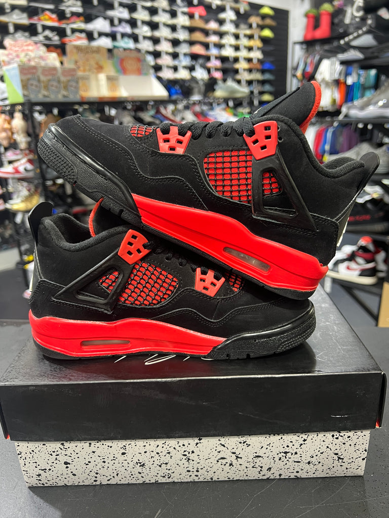 Black and red sneakers on a black platform with a blurred store background